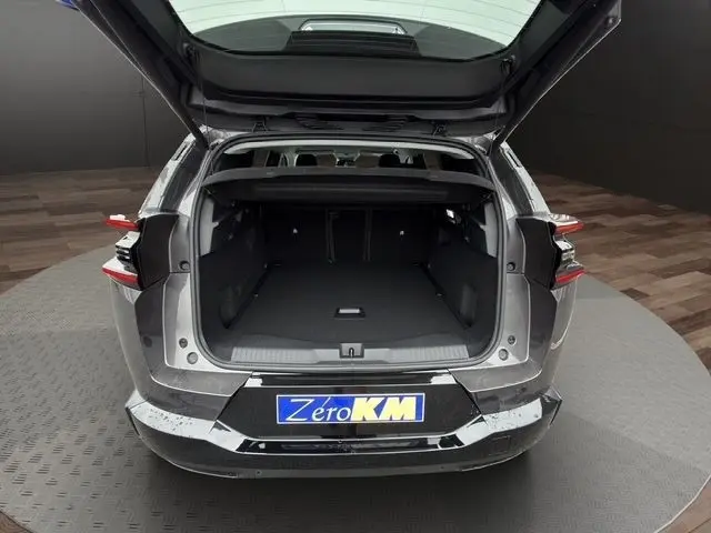 Vue arrière ouverte du coffre d'une Citroën C5 hybride gris foncé, montrant un espace de chargement spacieux et propre.