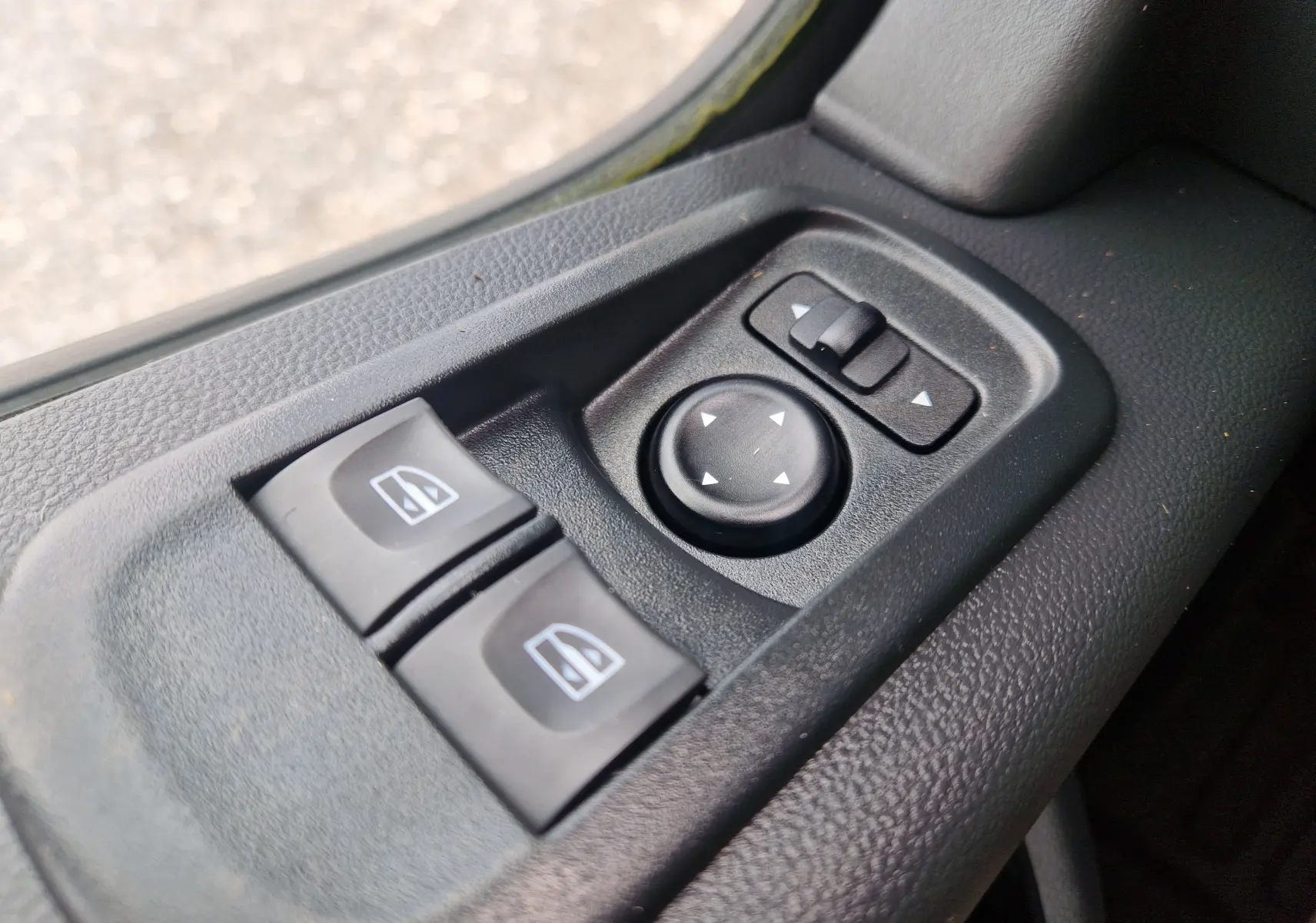 Gros plan sur les commandes électriques des vitres et des rétroviseurs du côté gauche intérieur d’un Renault Master Châssis Cabine blanc.