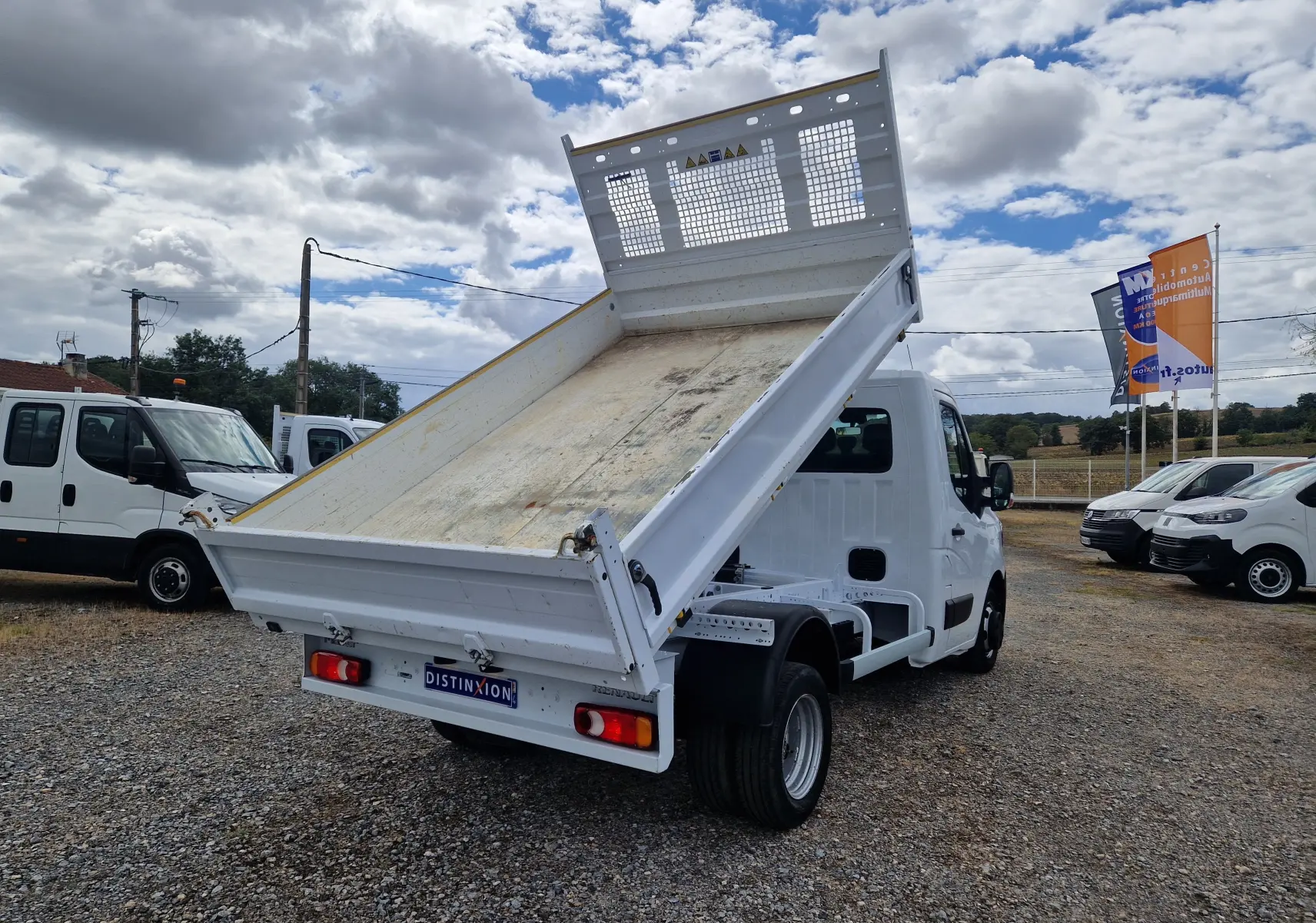 Renault Master Châssis cabine blanc vu 3/4 arrière avec benne basculante relevée et roues jumelées.