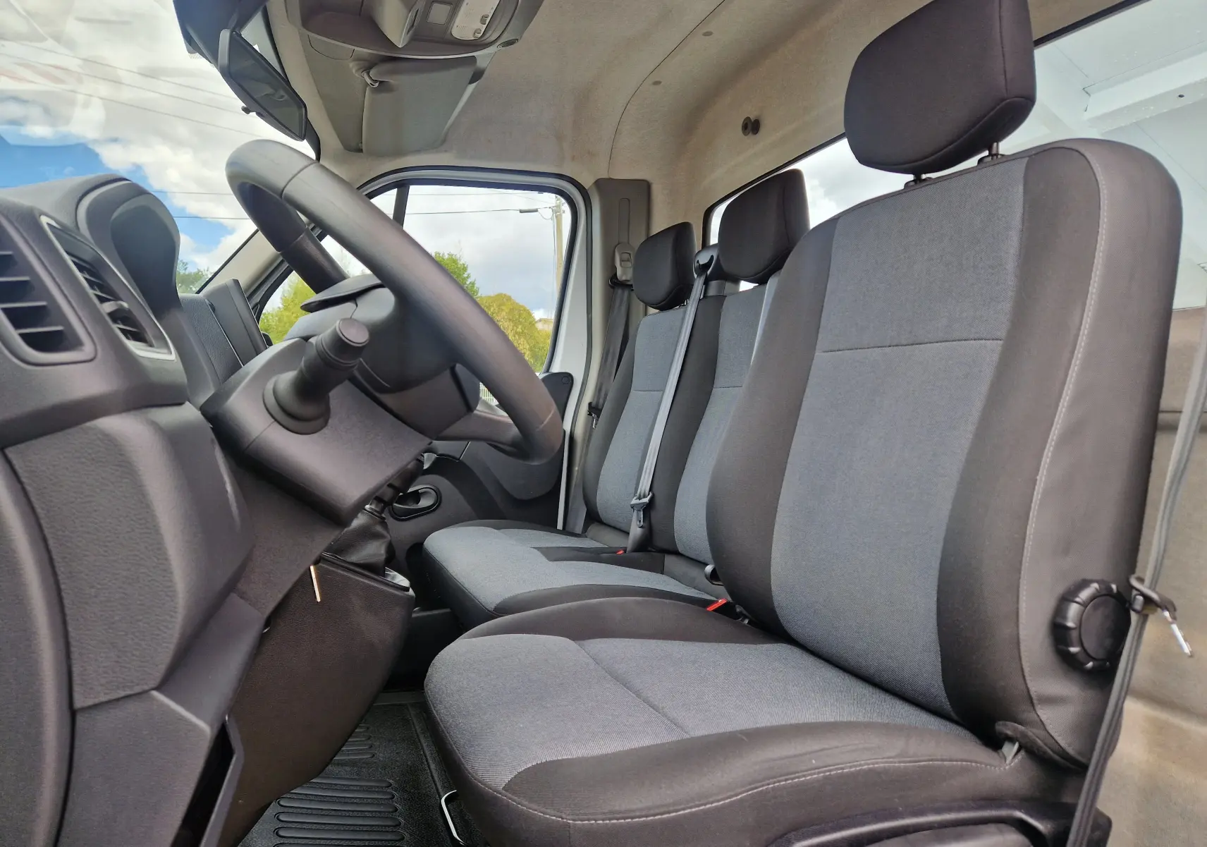 Vue intérieure côté conducteur du Renault Master Châssis Cabine 2024, montrant les sièges gris et noirs et le volant.