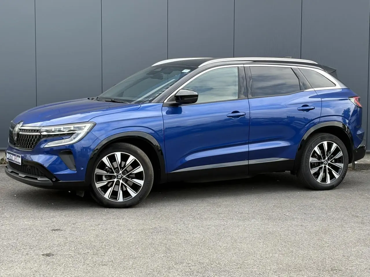 Vue de profil côté gauche du Renault Austral E-Tech en bleu Iron avec toit noir panoramique et jantes alliage 19 pouces.