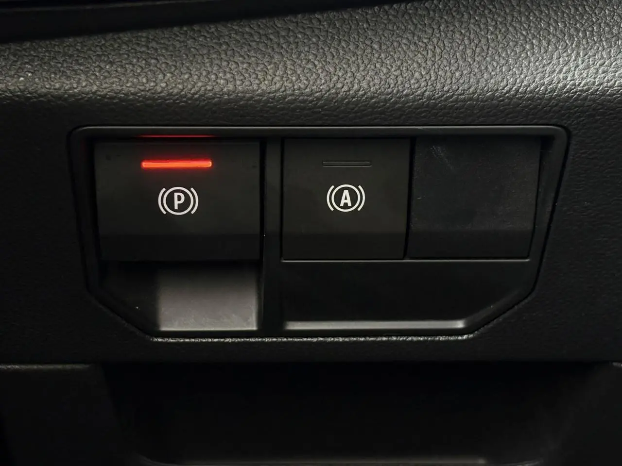 Gros plan sur les boutons de frein de parking électrique et auto-hold dans l’habitacle du Renault Austral 2025.