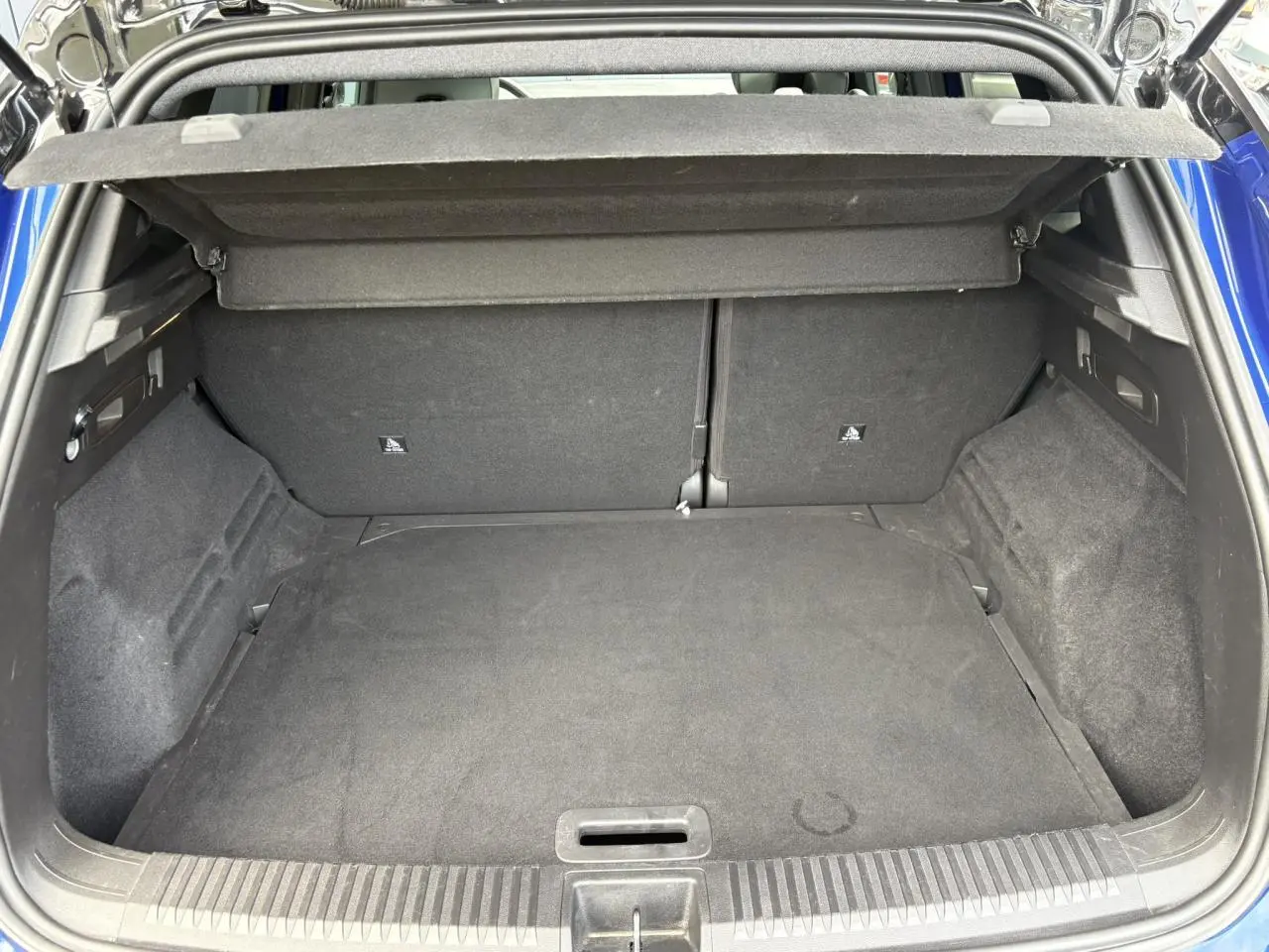 Coffre ouvert vu de l'arrière d'un Renault Austral Bleu Iron, montrant un espace de chargement vide et propre.