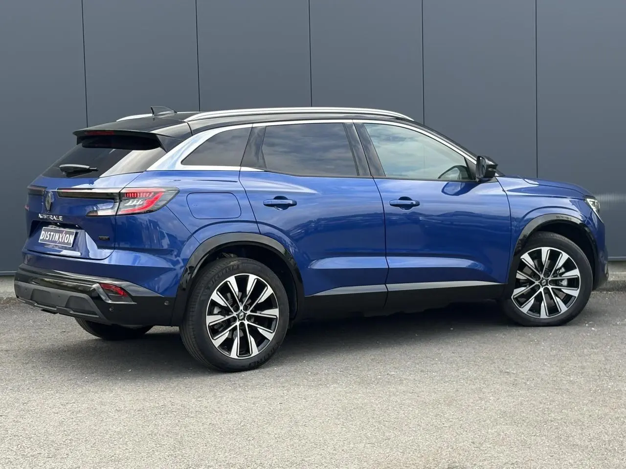 Vue de profil côté droit du Renault Austral E-Tech Full Hybrid 200 Techno bleu Iron avec toit panoramique et jantes alliage noires.