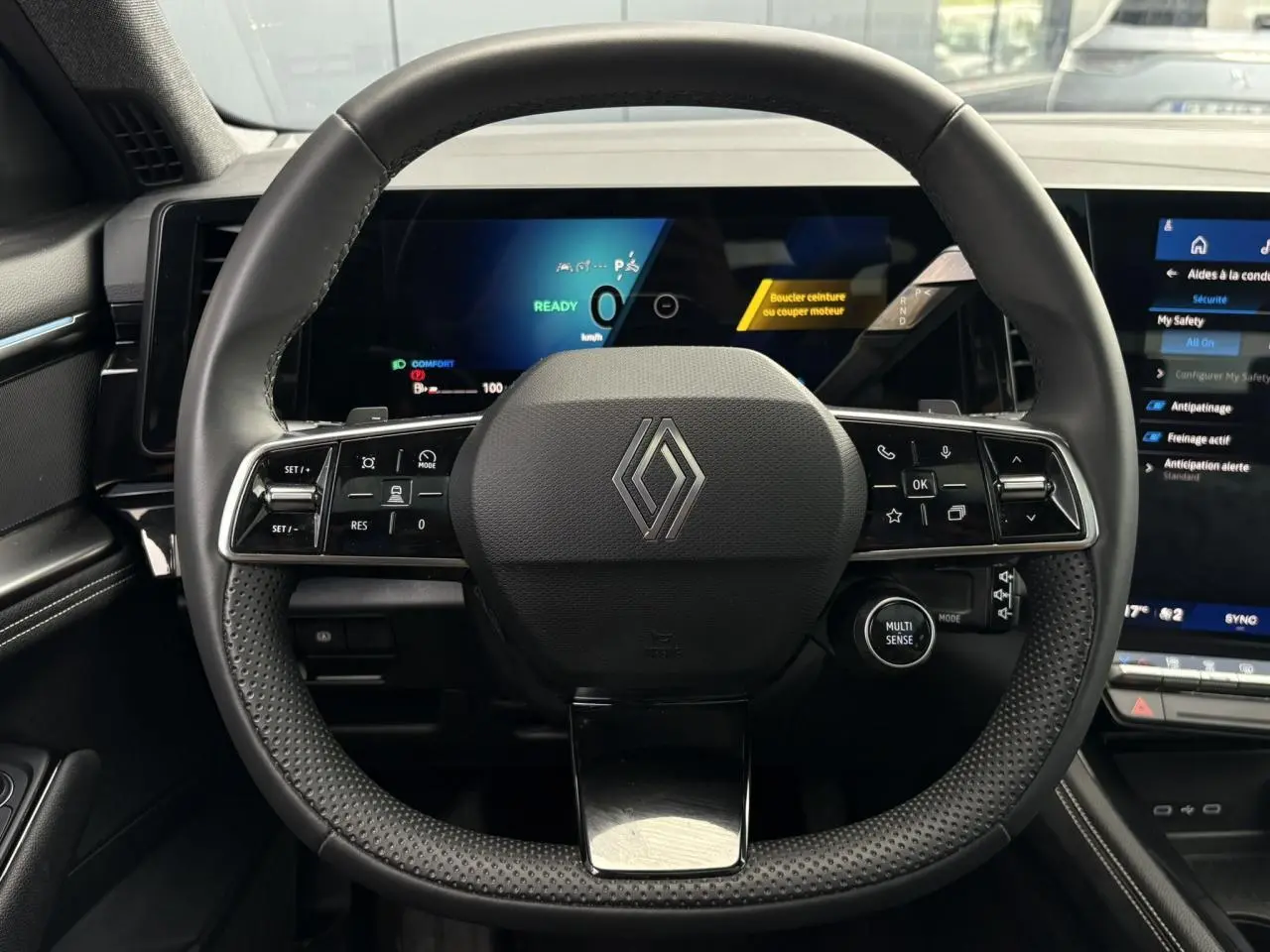 Vue frontale du volant noir texturé du Renault Austral 2025 avec tableau de bord numérique et écran tactile latéral.