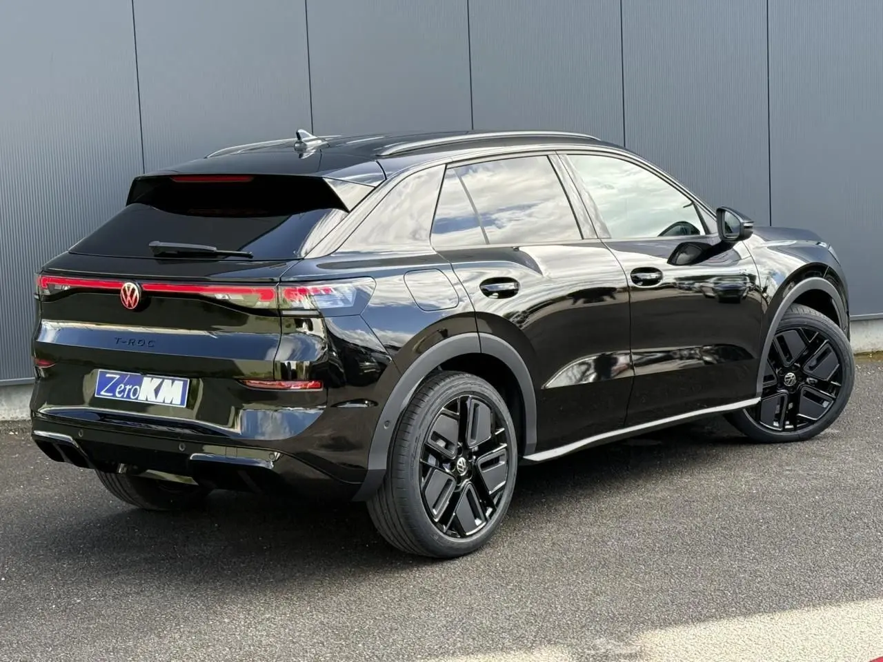 Volkswagen T-Roc noir ébène en 3/4 arrière droit, avec jantes noires sport et vitres surteintées.