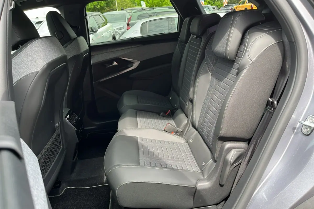 Vue intérieure côté droit des sièges arrière en tissu et cuir du Peugeot 3008 Hybrid 2025 gris artense avec toit noir.