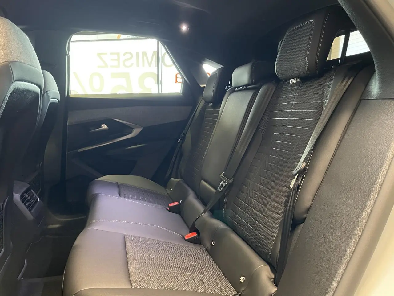 Vue latérale droite de la banquette arrière en tissu noir du Peugeot 3008 Hybrid 2025 avec ceintures et appuie-têtes.