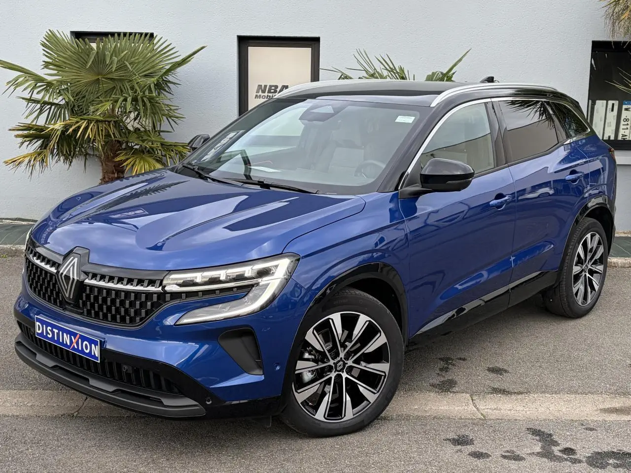 Renault Austral E-Tech bleu Iron avec toit noir panoramique, vue 3/4 avant droit mettant en valeur ses jantes 19 pouces.