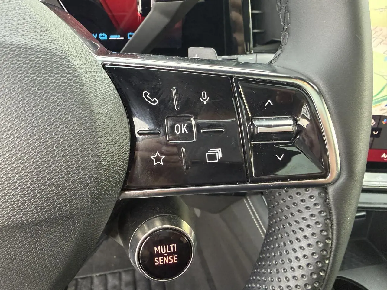 Gros plan sur les commandes au volant et le bouton Multi-Sense du Renault Austral E-Tech hybride 2025, intérieur noir.