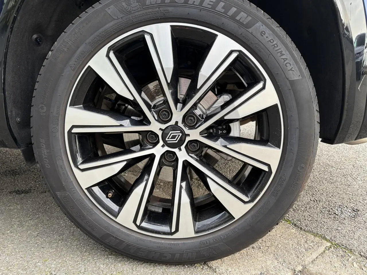 Gros plan sur la jante alliage 19 pouces Komah diamantée noire du Renault Austral E-Tech Bleu Iron.