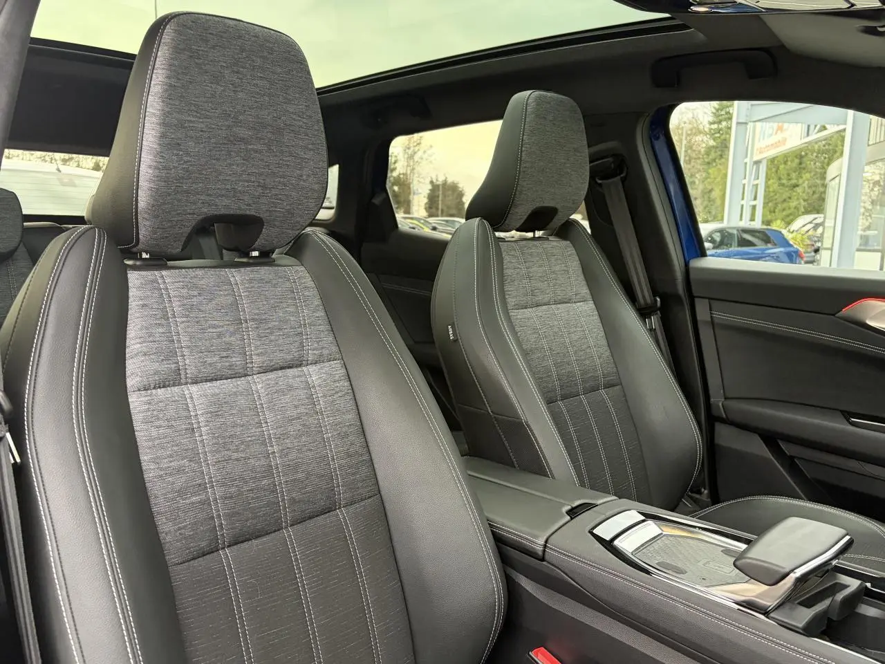 Vue intérieure sur les sièges avant gris et noir du Renault Austral E-Tech 2025 avec toit panoramique et console centrale.