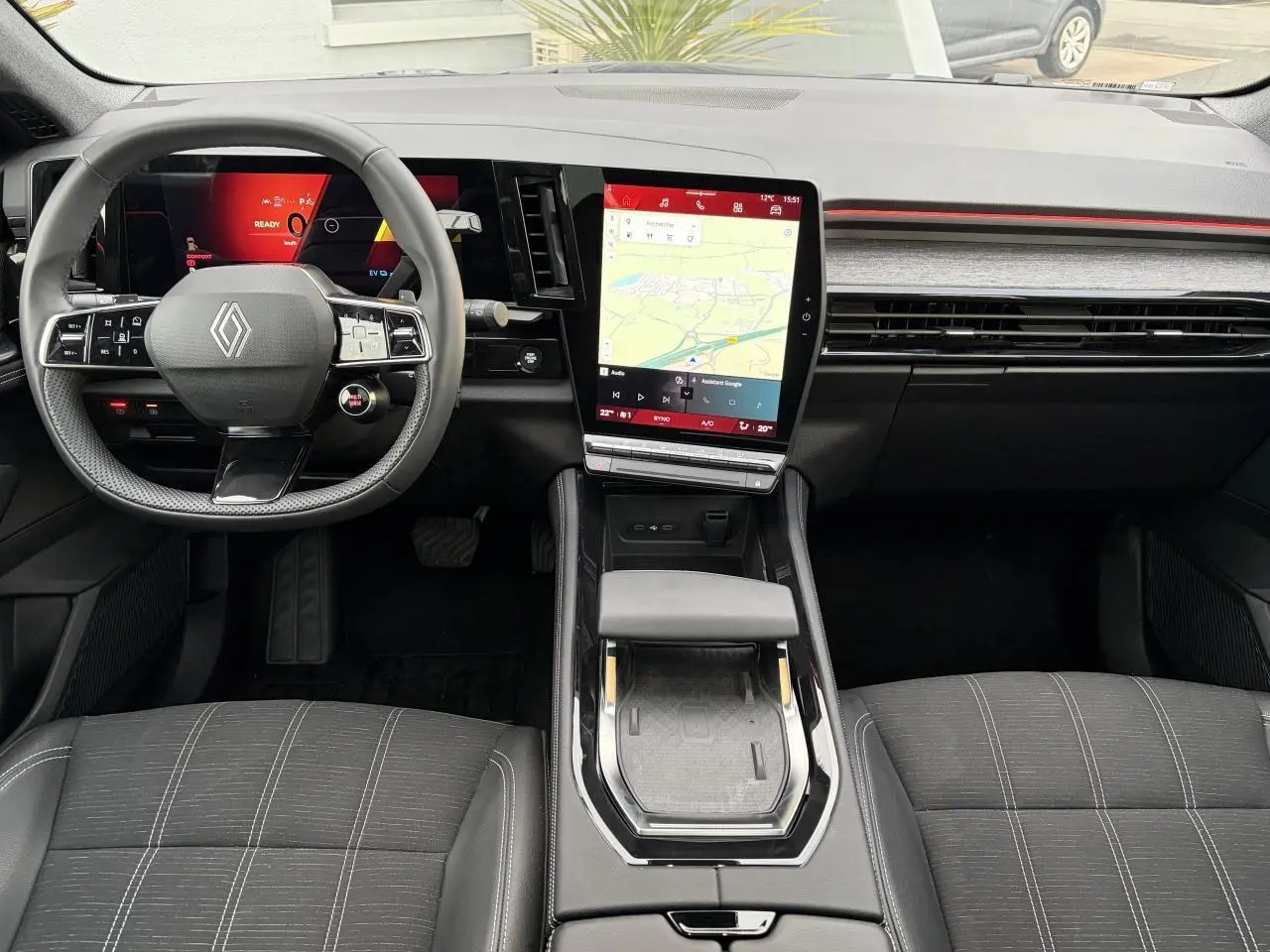 Vue intérieure avant du Renault Austral E-Tech 2025, tableau de bord noir avec écran tactile vertical et volant compact.