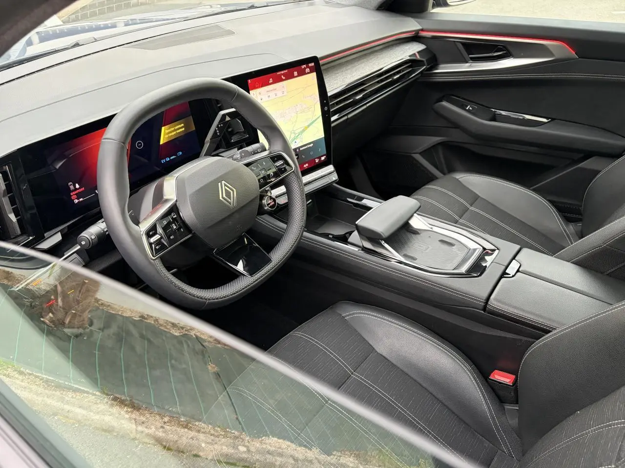 Vue intérieure côté conducteur du Renault Austral E-Tech 2025, avec tableau de bord numérique et écran tactile vertical.