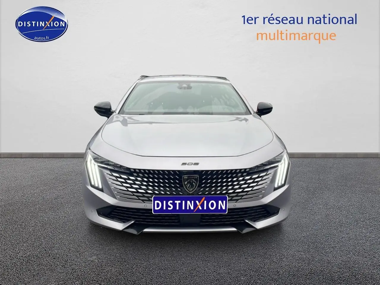 Vue avant centrée d'une Peugeot 508 SW gris artense avec calandre chromée et feux LED verticaux allumés.