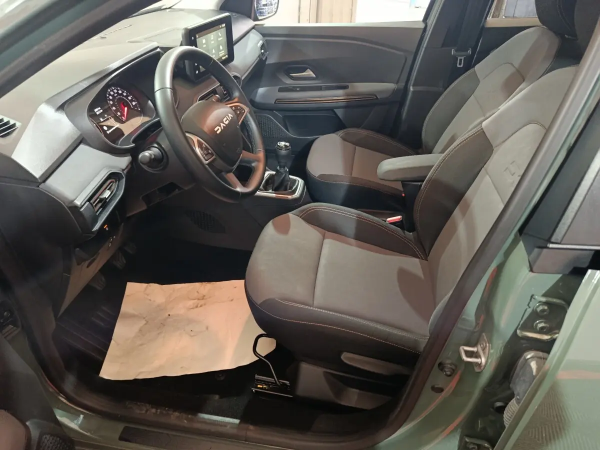 Vue intérieure côté conducteur de la Dacia Sandero Extreme+ TCe 110 2024, sièges gris et volant multifonction cuir.