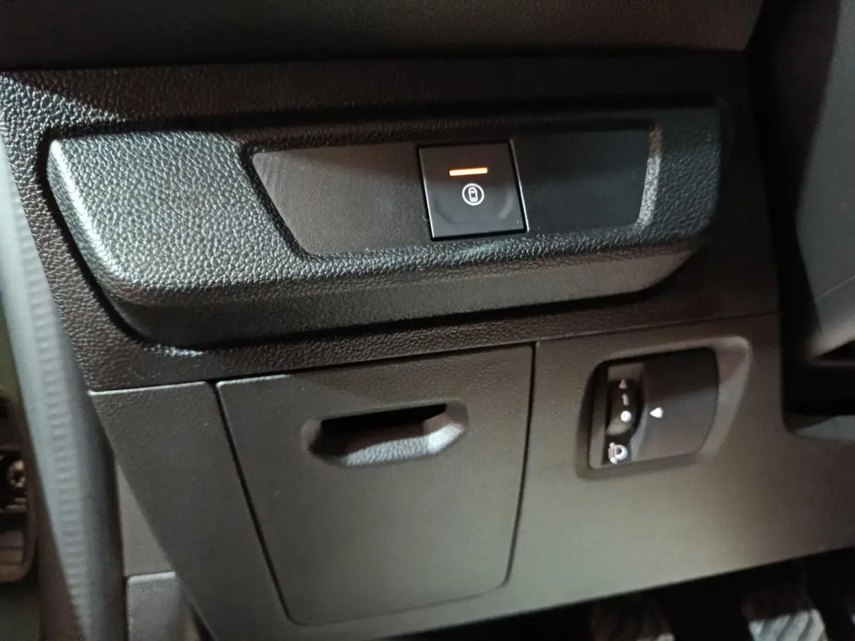 Détail intérieur montrant le bouton de condamnation centralisée et réglage des phares sur la planche de bord côté conducteur.