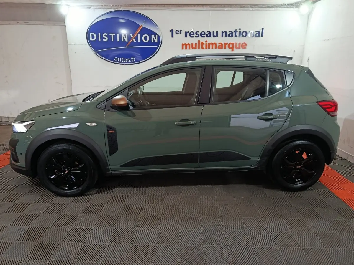 Vue de profil droit d'une Dacia Sandero Extreme+ TCe 110 2024 verte avec jantes noires et rails de toit assortis.