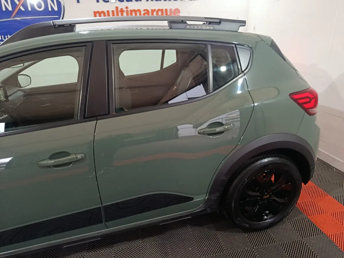 Vue latérale droite d'une Dacia Sandero Extreme+ TCe 110 2024 verte avec jantes noires et rails de toit assortis.