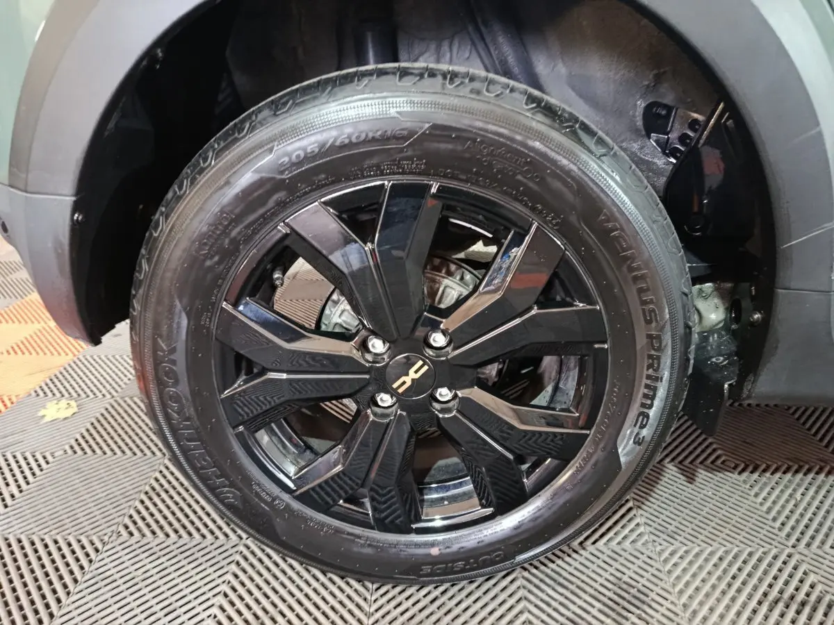 Gros plan sur la roue avant droite noire brillante du Dacia Sandero Extreme+ TCe 110 vert 2024 avec jante en alliage.