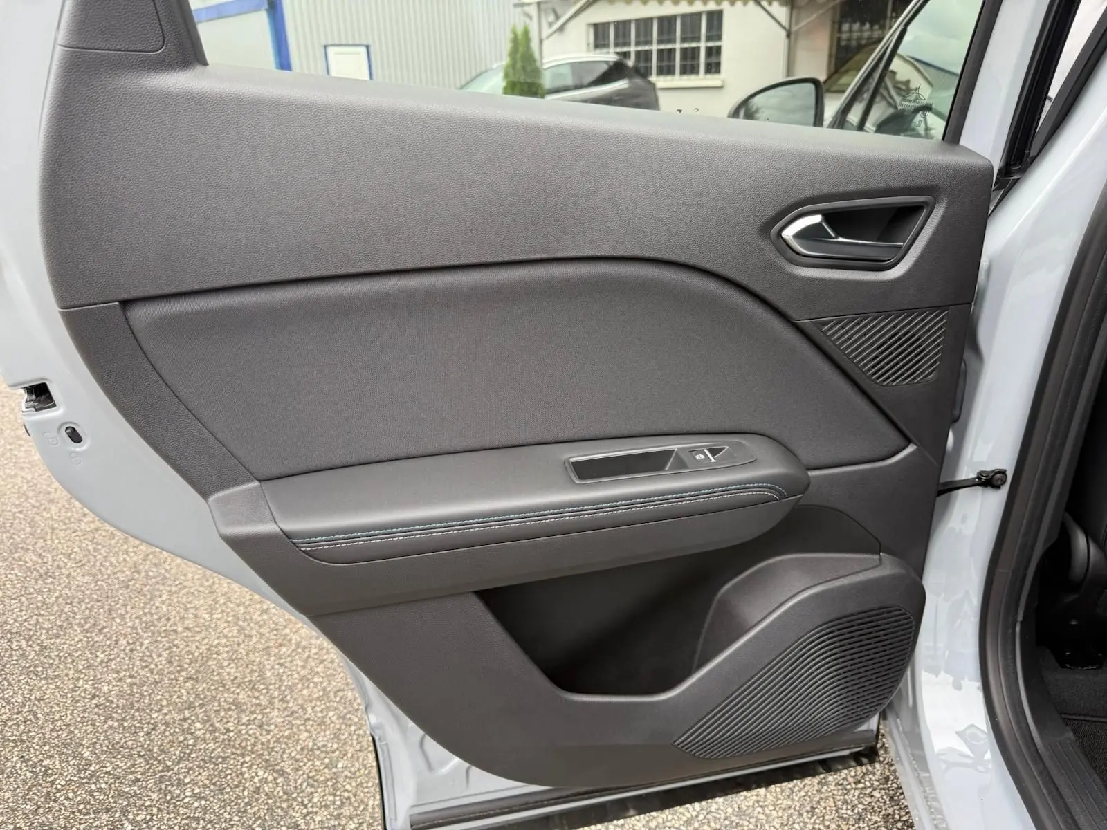 Vue rapprochée de la porte arrière droite gris rafale du Renault Symbioz 2026, avec commande de vitre et haut-parleur intégré.