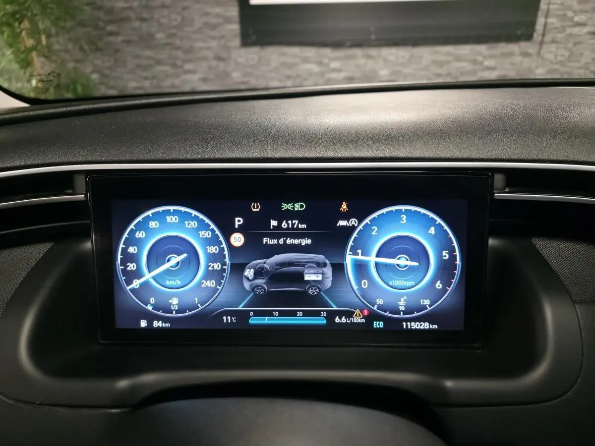 Tableau de bord numérique du Hyundai Tucson 2020, affichage bleu avec vitesse, régime et flux d'énergie.