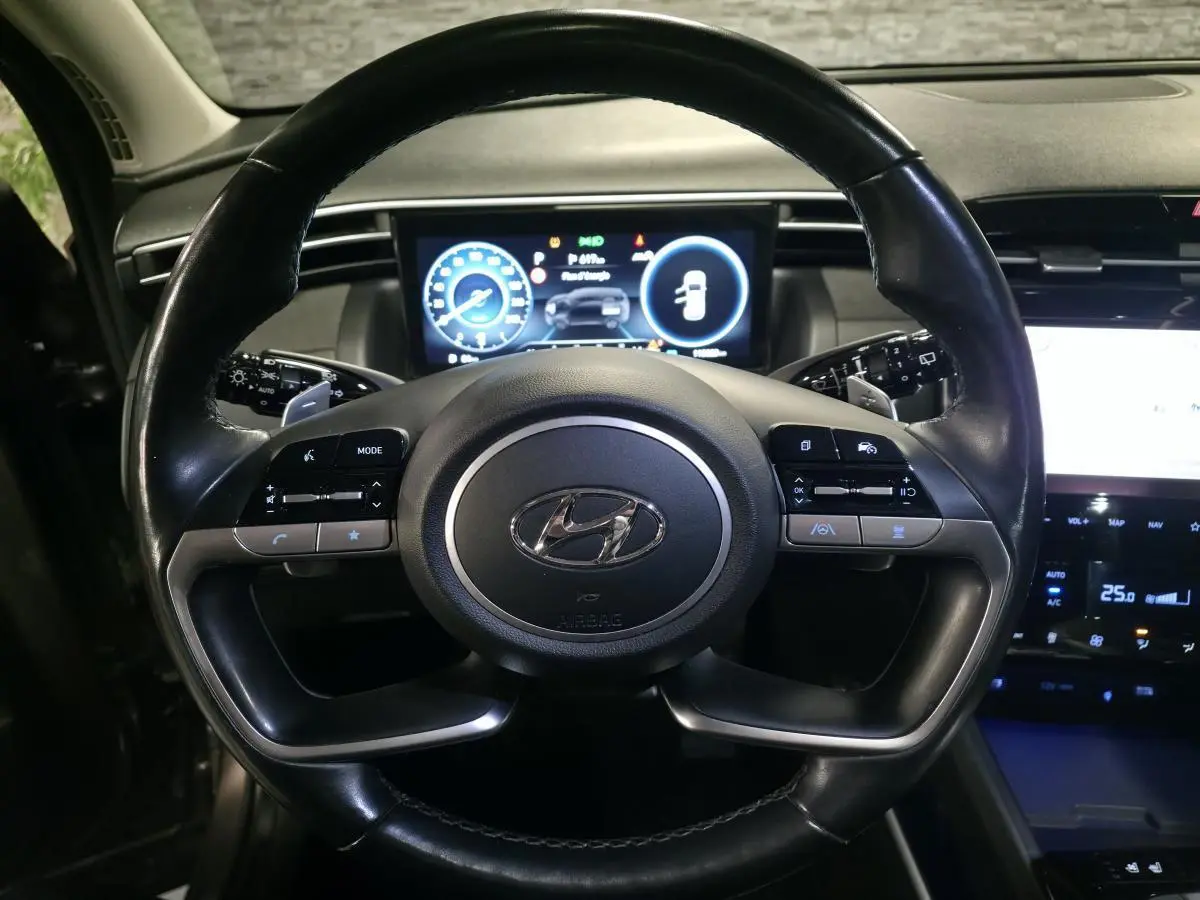 Vue rapprochée du volant cuir noir du Hyundai Tucson 2020 avec tableau de bord numérique et commandes intégrées.