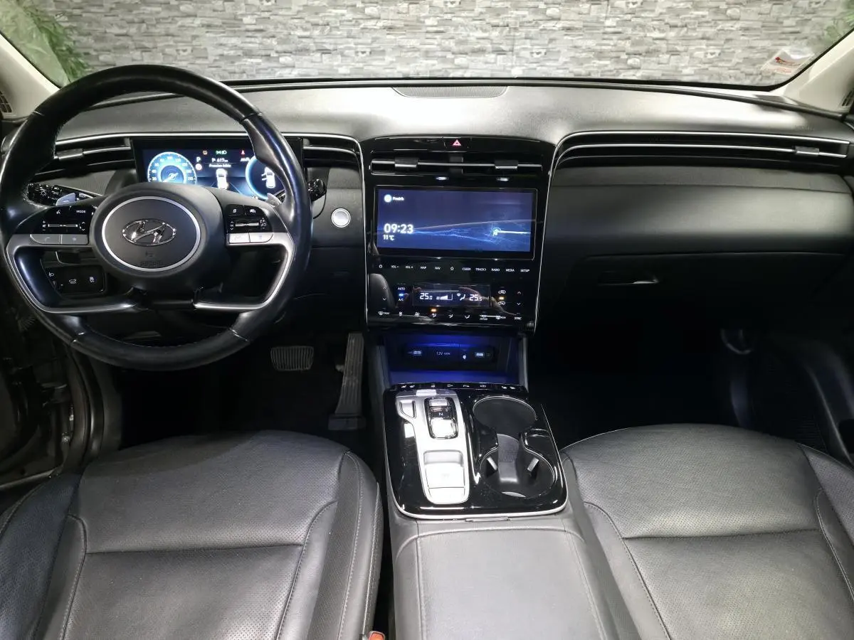 Vue intérieure avant du Hyundai Tucson 2020, tableau de bord noir avec écran tactile central et volant multifonction cuir.