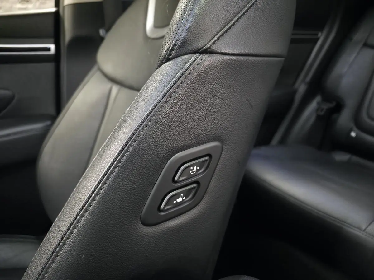 Détail des commandes de réglage sur le côté du siège avant en cuir noir du Hyundai Tucson gris.