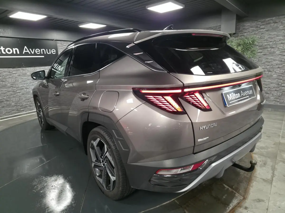 Vue 3/4 arrière droite d’un Hyundai Tucson gris métallisé avec feux arrière LED et jantes alliage 19 pouces.