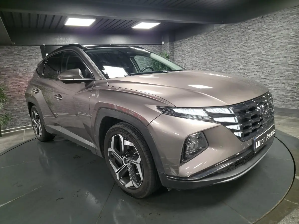 Vue 3/4 avant droit du Hyundai Tucson gris métallisé avec calandre chromée et jantes alliage 19 pouces.