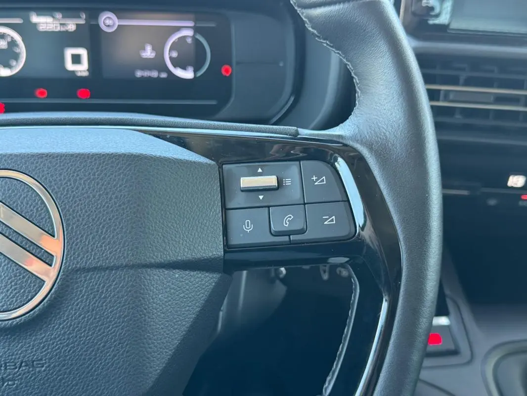Vue rapprochée du volant noir du Citroën Berlingo vert 2024, avec commandes audio et téléphone intégrées.