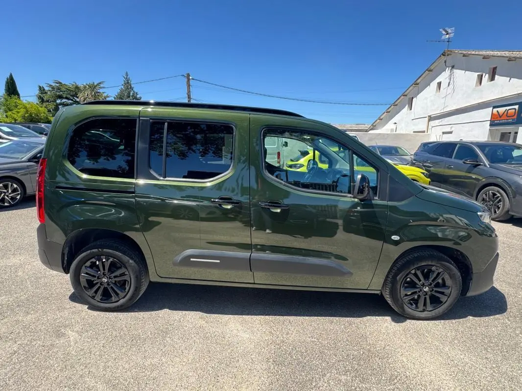 Vue de profil côté droit du Citroën Berlingo vert foncé 2024 avec barres de toit et jantes noires.