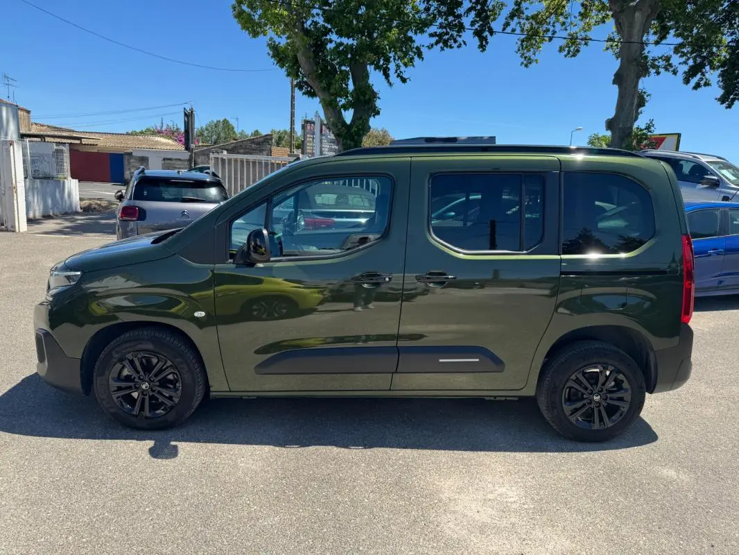 Vue de profil côté gauche d'un Citroën Berlingo vert 2024 avec barres de toit et jantes noires.