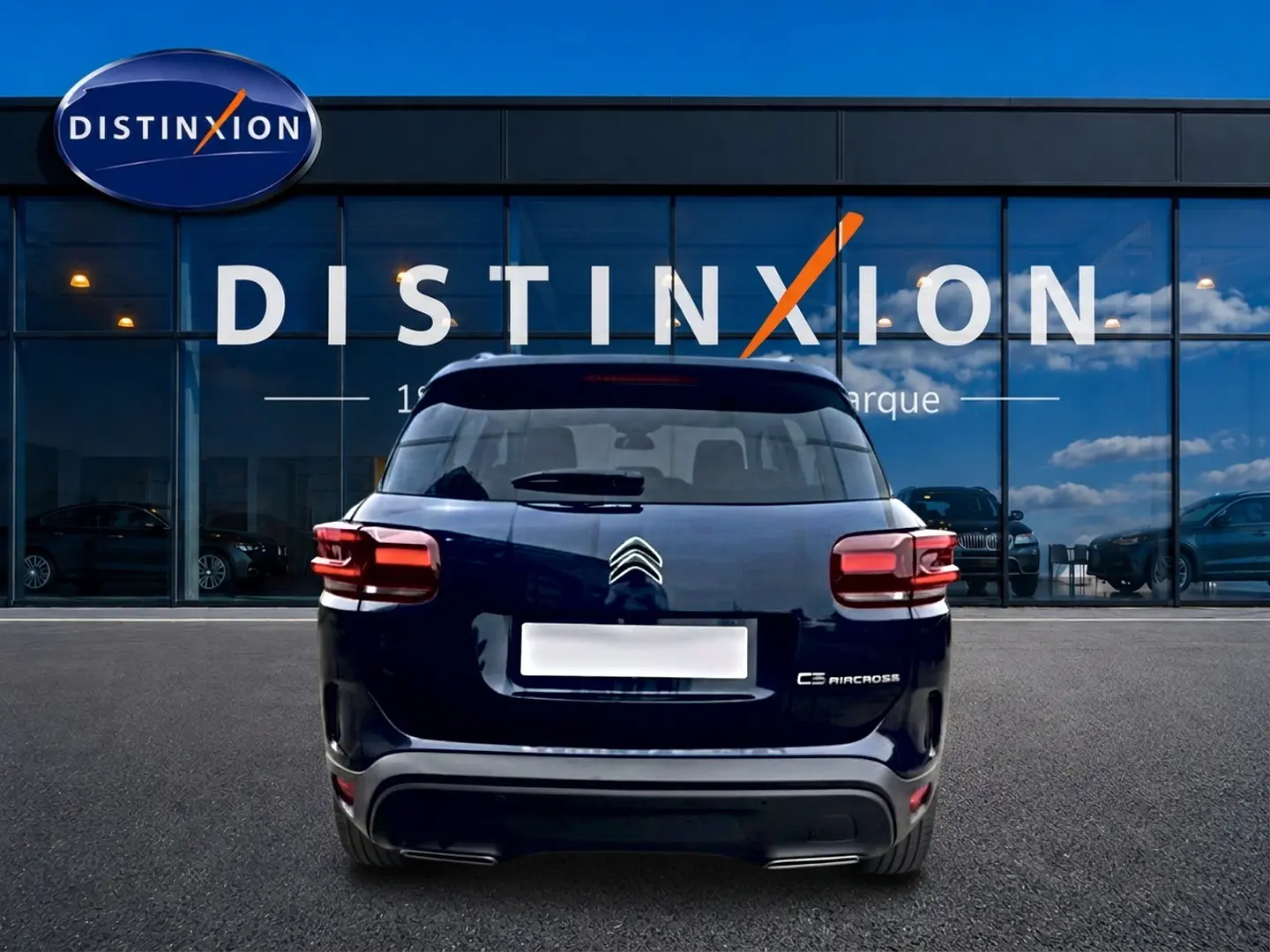 Vue arrière d’un Citroën C5 Aircross bleu eclipse garé devant une vitrine avec logo Distinxion.