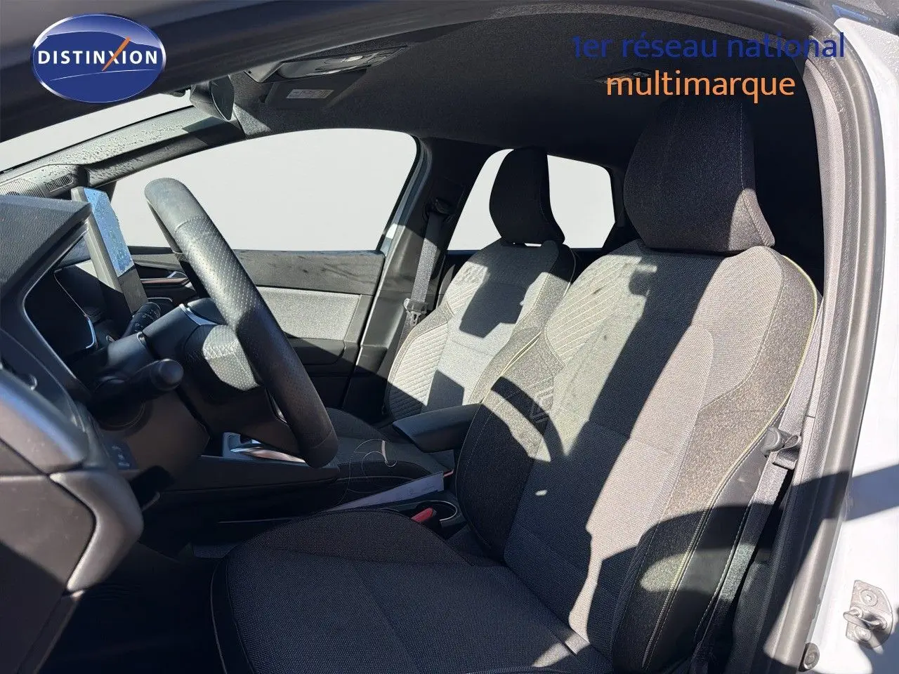 Vue intérieure côté conducteur de la Renault Symbioz 2025, sièges tissu gris clair et volant cuir noir.