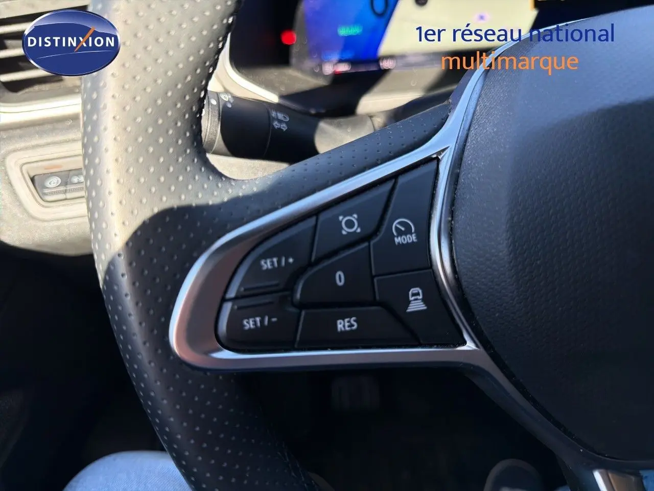 Gros plan sur les commandes au volant perforé noir du Renault Symbioz 2025, version hybride gris Rafale métal.