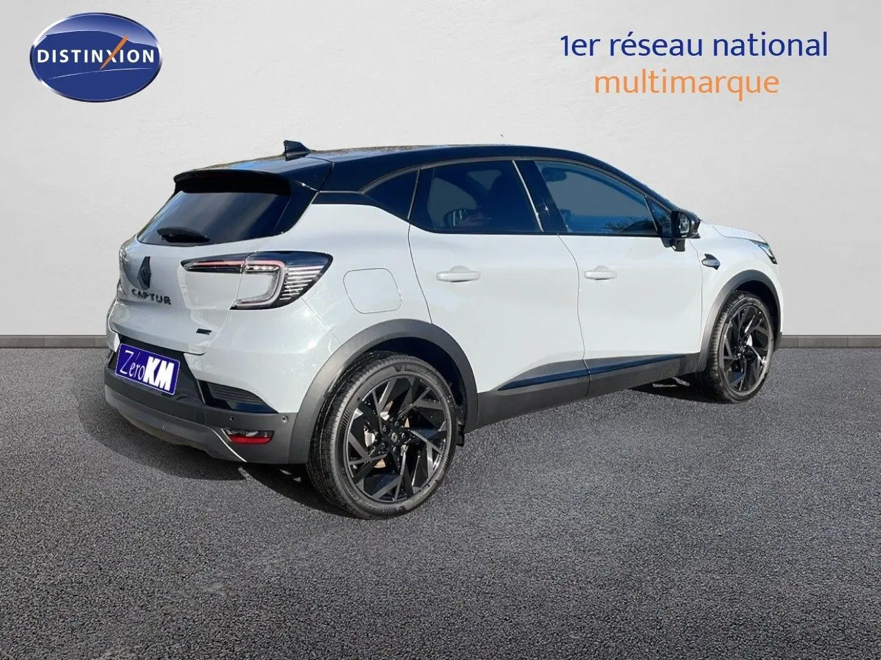 Vue 3/4 arrière droite d'un Renault Captur E-Tech hybride 2025 blanc avec toit noir et jantes noires.
