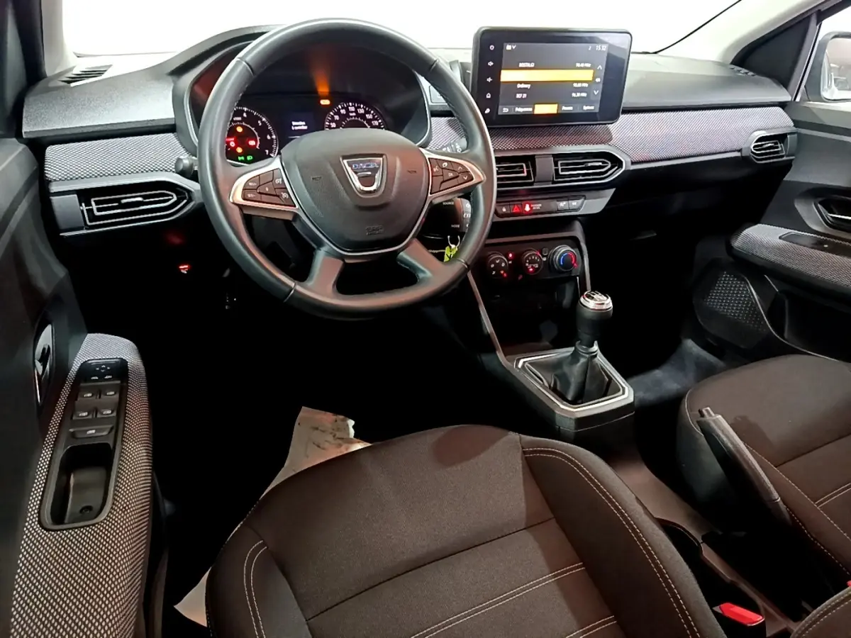 Vue intérieure côté conducteur de la Dacia Sandero 2022, volant cuir multifonctions et écran tactile central visible.