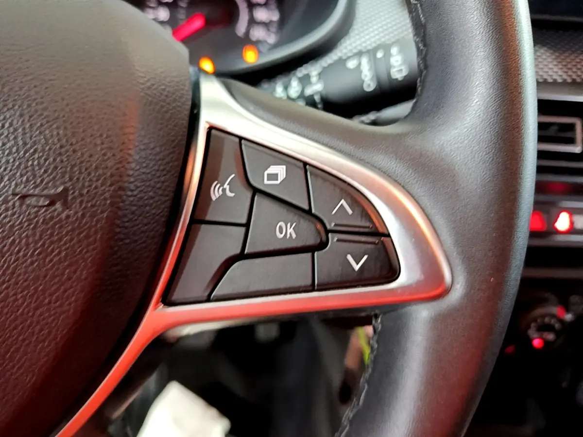 Gros plan sur les commandes multifonctions à droite du volant cuir synthétique de la Dacia Sandero Confort TCe 90 blanche 2022.