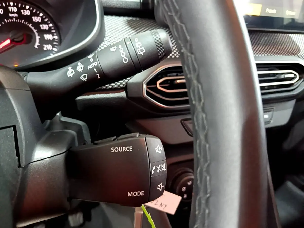 Gros plan sur le volant cuir synthétique et commandes multifonctions de la Dacia Sandero Confort TCe 90 2022.