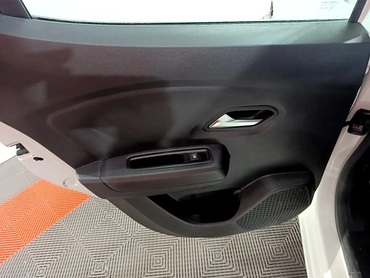 Vue rapprochée de la porte arrière droite noire d'une Dacia Sandero blanche 2022, avec poignée et commande de vitre électrique.