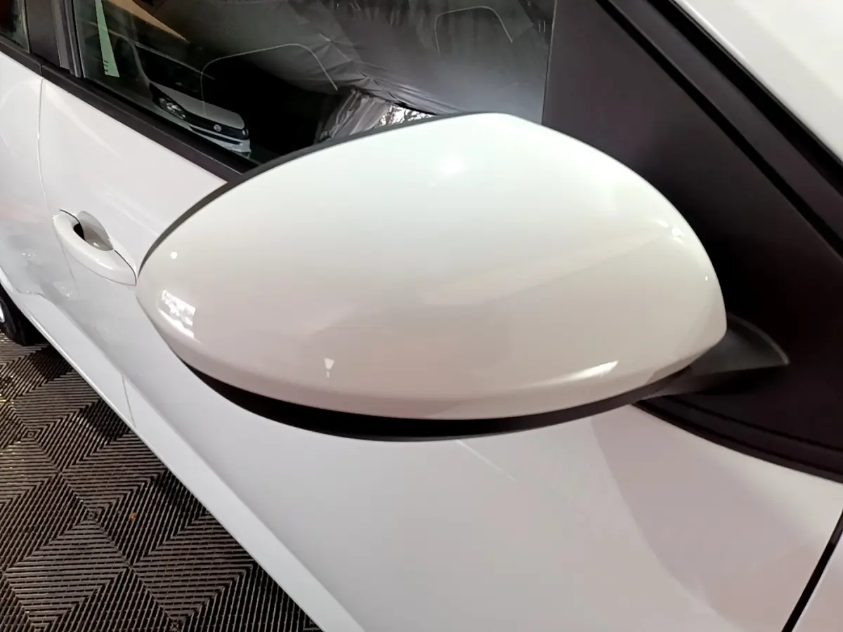 Gros plan sur le rétroviseur côté gauche blanc d'une Dacia Sandero Confort TCe 90 de 2022, carrosserie blanche visible.