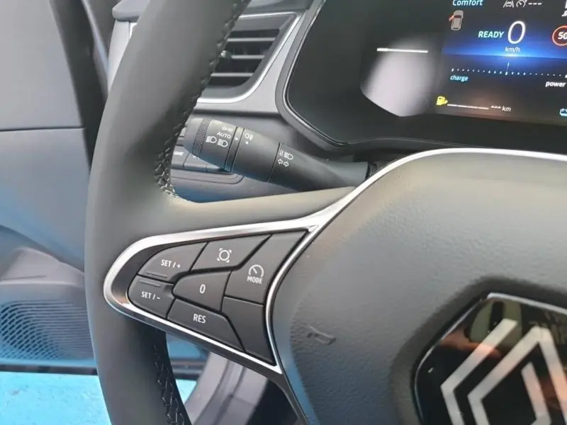 Gros plan sur le volant multifonction noir du Renault Captur gris Cassiopée, avec commandes de régulateur et tableau de bord numérique.