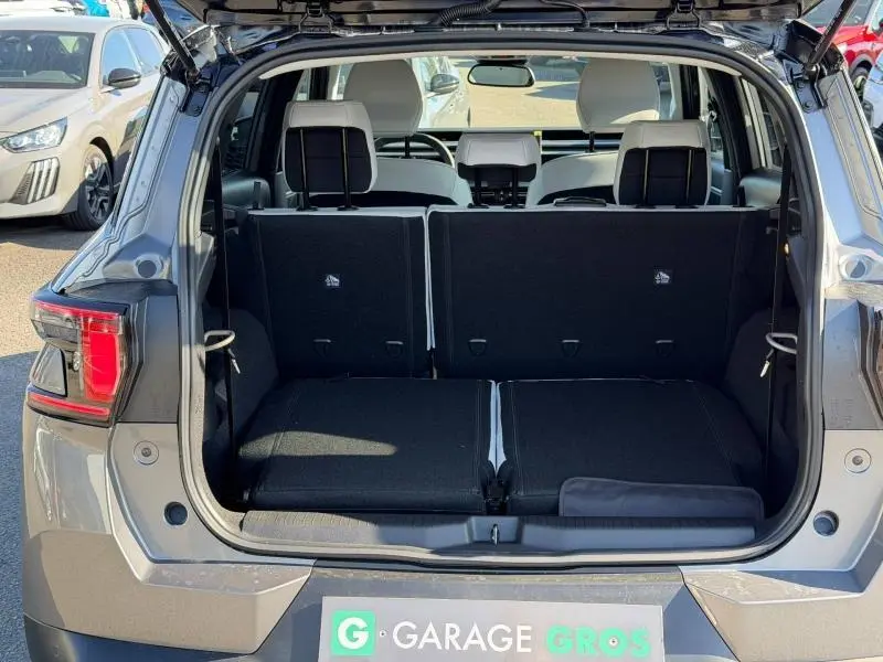 Coffre ouvert en vue arrière d’un Citroën C3 Aircross gris Mercury avec sièges arrière rabattus et intérieur clair.