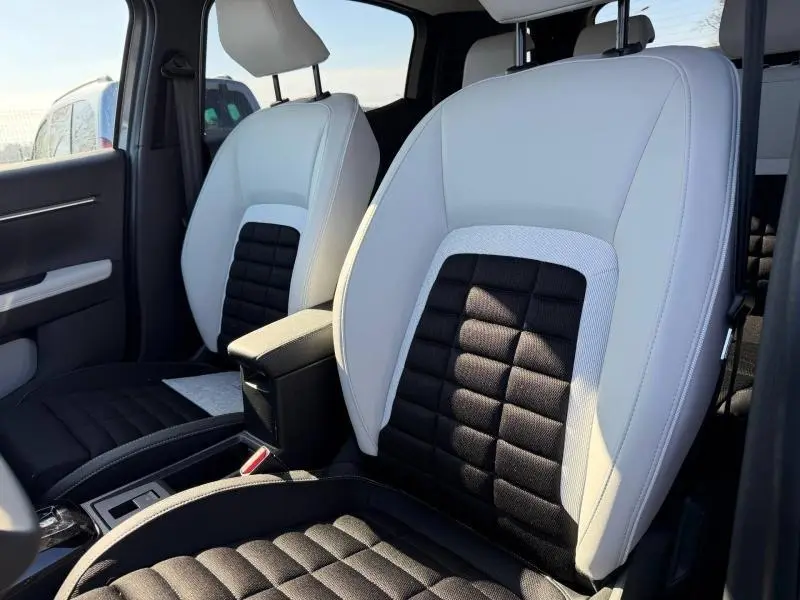 Vue rapprochée des sièges avant bicolores gris clair et noir du Citroën C3 Aircross 2026, intérieur lumineux.