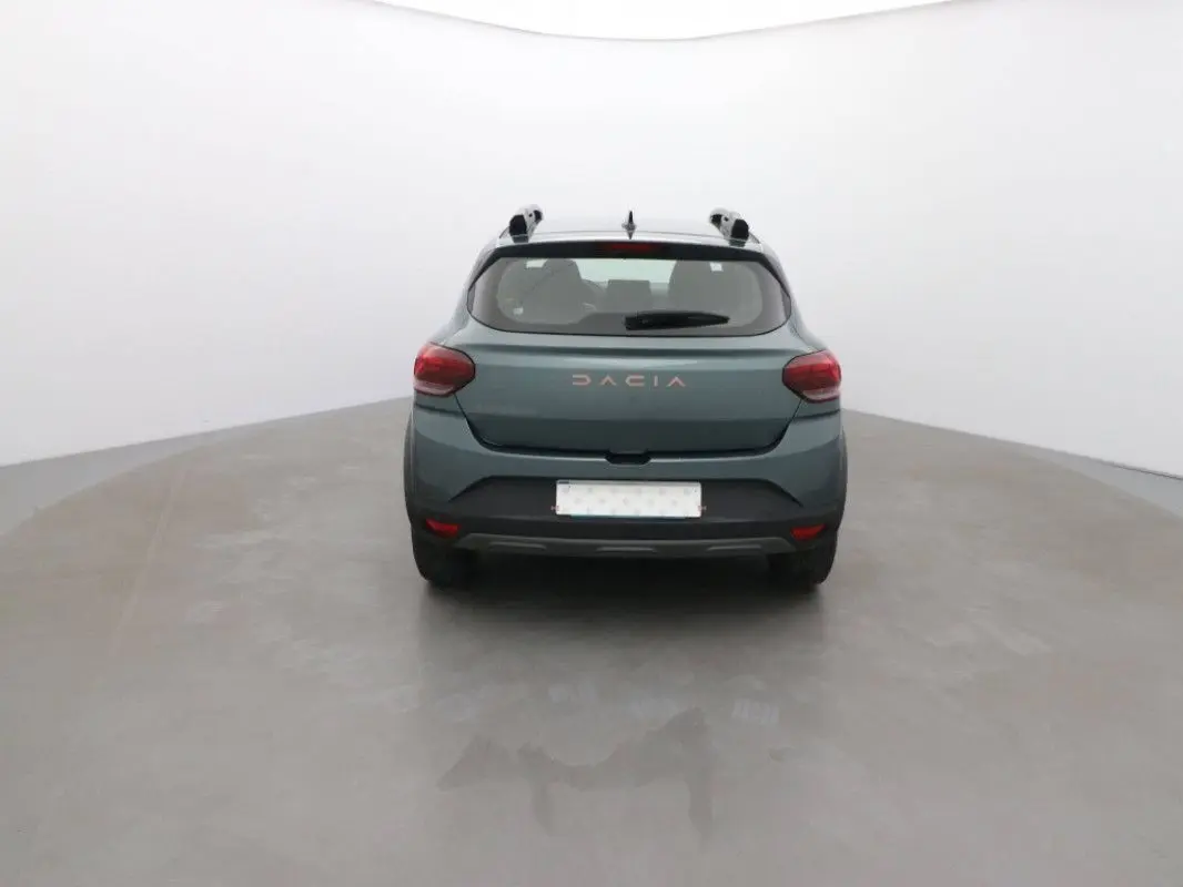 Vue arrière d'une Dacia Sandero Stepway 2025 vert cèdre, avec logo et feux arrière visibles dans un studio neutre.