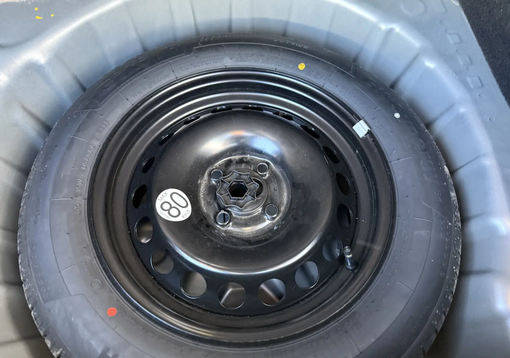 Gros plan sur la roue de secours noire montée sur jante acier, logée dans le coffre du Dacia Sandero Stepway 2025.