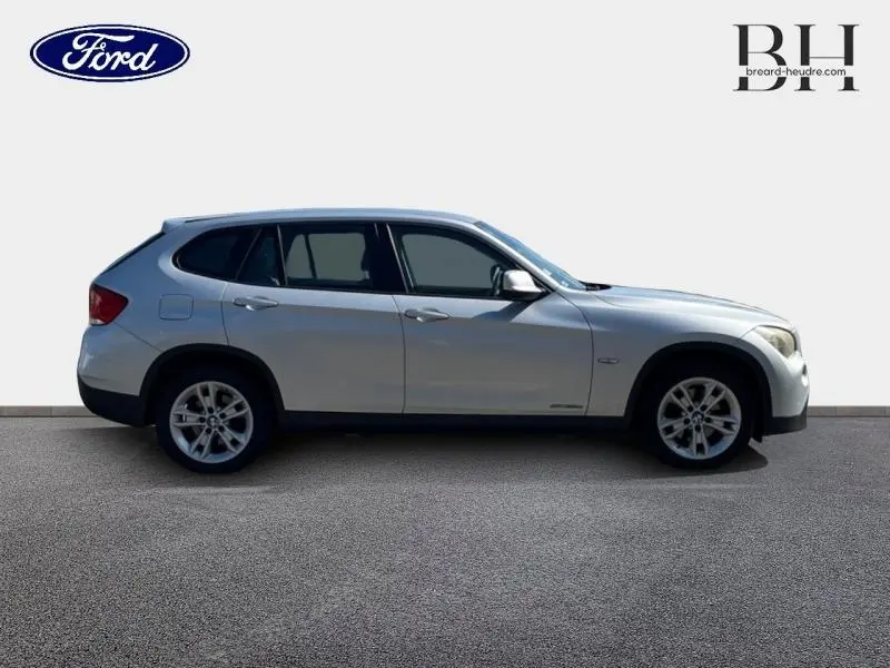 Vue de profil côté gauche d’un BMW X1 gris métallisé avec jantes alu 17 pouces sur fond neutre.