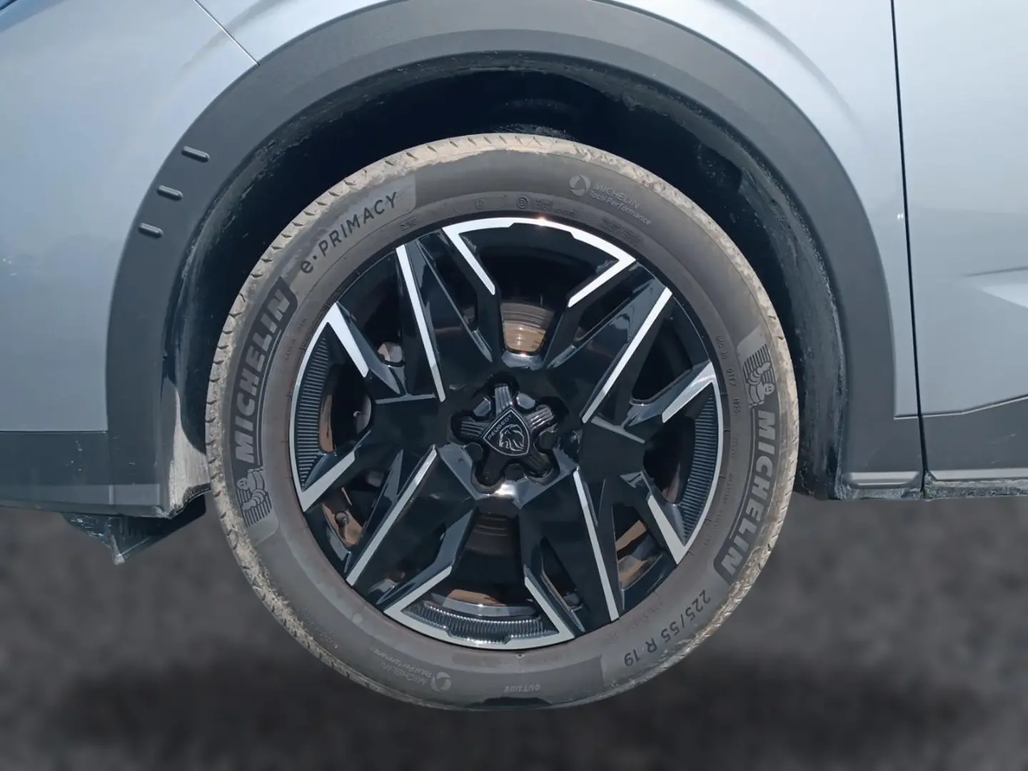 Gros plan sur la roue avant droite du Peugeot 5008 gris Artense avec jante alliage noire et inserts argentés.